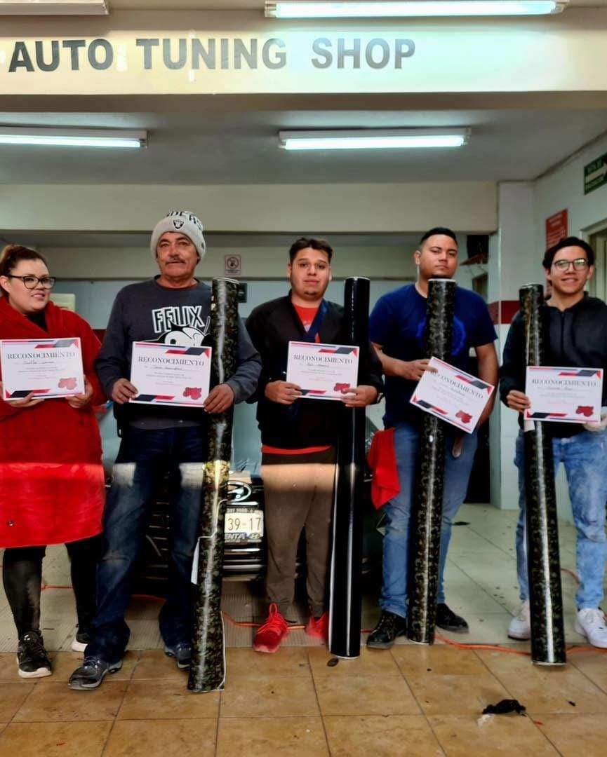 Egresados de la Escuela de Wrap mostrando su certificado, en las instalaciones de Auto Tuning Shop