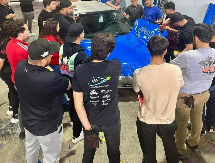 Grupo de alumnos instalando wrap azul en un auto deportivo