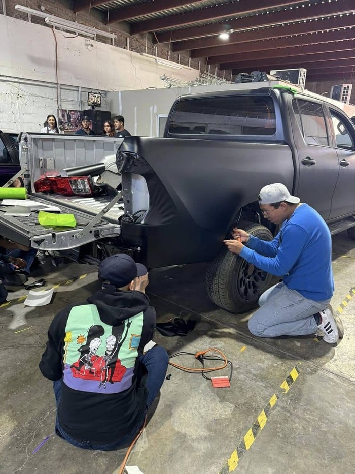 Alumnos instalando wrap mate negro en una camioneta
